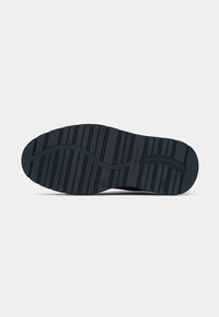 Semelle de chaussure en caoutchouc noir avec des rainures horizontales et un texte indiquant la taille et la marque sur un fond clair uni.