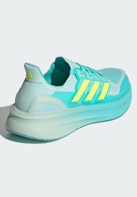 Baskets de running bleu aqua avec tige en mesh, rayures jaune fluo et semelle amortissante. Elles présentent un talon prononcé et un tissu texturé.