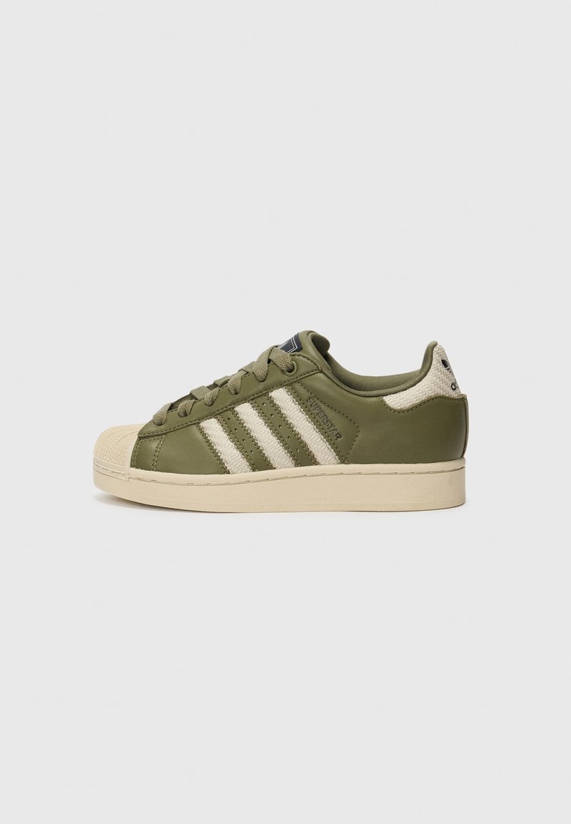Olive green sneaker with a textured leather upper, cream accents, and three horizontal stripes; features a rubber toe cap and flat laces.