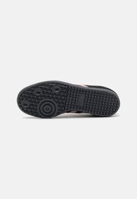 Fekete sneaker talp, textúrált mintával, kör alakú kidomborodásokkal és logóval. A cipő tartós gumi anyagból készült, és jellegzetes megjelenéssel bír.