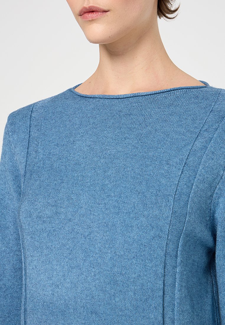 Pull bleu clair avec encolure ronde, tissu légèrement texturé et coutures décoratives sur les épaules et les côtés.