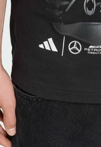 Black cotton t-shirt with a graphic print, featuring white Adidas and Mercedes-Benz logos, round neck, and short sleeves.