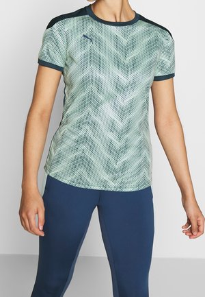Camiseta deportiva de manga corta en verde y negro con un diseño geométrico, cuello redondo y sin cierres ni adornos visibles.