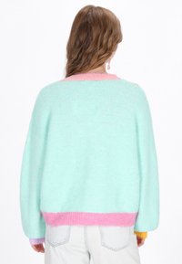 Hellblaues, übergroßes Sweatshirt mit pinken und lavendelfarbenen Akzenten an den Ärmeln und am Saum. Hergestellt aus kuscheligem Material, mit Rundhalsausschnitt und lässiger Passform.