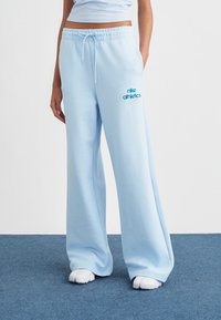 Világoskék melegítőnadrág puha anyagból, elasztikus derékrésszel és húzózsinórral, "Nike Athletics" kék logóval.