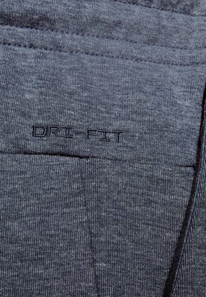 Šedá Dri-Fit tkanina s textúrovaným pleteným vzorom. Obsahuje prešívané detaily a viditeľné logo. Mäkký, ľahký materiál.
