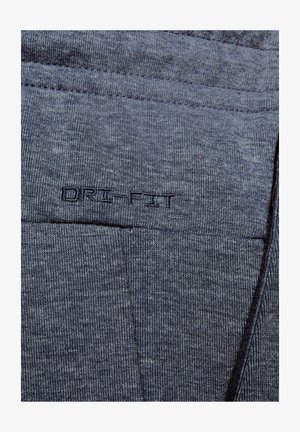 Szary materiał Dri-Fit z teksturowanym wzorem dzianiny. Zawiera wyszywane detale oraz widoczne logo. Miękki, lekki materiał.