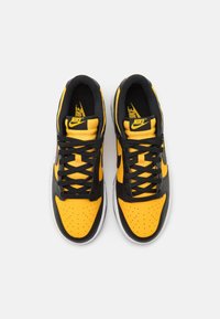 Svarta och gula Nike-sneakers med perforerat tår, svarta snören och vadderad krage. Designen har en vit sula och logotypdetaljer.