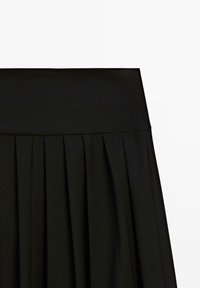 Jupe plissée noire avec large ceinture, présentée sur fond blanc.