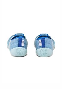 Zapatos de tela azul con una parte superior texturizada, correas ajustables y suelas azul claro. Presentan un logo en el talón y un diseño suave y acolchado.