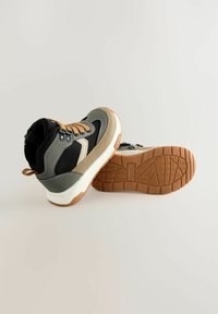 Sneakers w typie mid-top z połączeniem czarnej siateczki, szarego zamszu i tanowych akcentów. Teksturowana gumowa podeszwa z wzorem zapewniającym przyczepność.