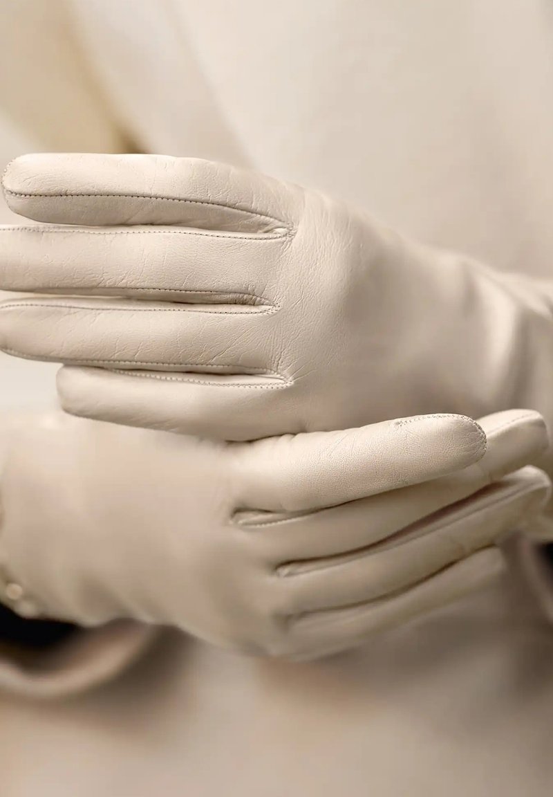 Leren handschoenen, crèmekleurig, met een gladde textuur, gedetailleerde stiksels en een aansluitend ontwerp, met naden langs de vingers en bovenop.