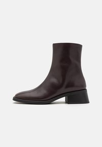 Brown leather ankle boot with a square toe, smooth finish, and a block heel. Features a textured black sole for grip.