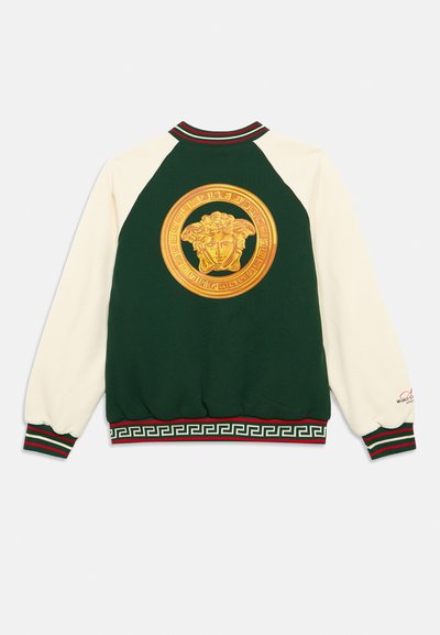 Πράσινη και κρεμ φούτερ με μεγάλο χρυσό έμβλημα της Μέδουσας στο πίσω μέρος, ριγέ ριμπ λαιμόκοψη και μανσέτες, και σχέδιο ελληνικού κλειδιού στη ζώνη.