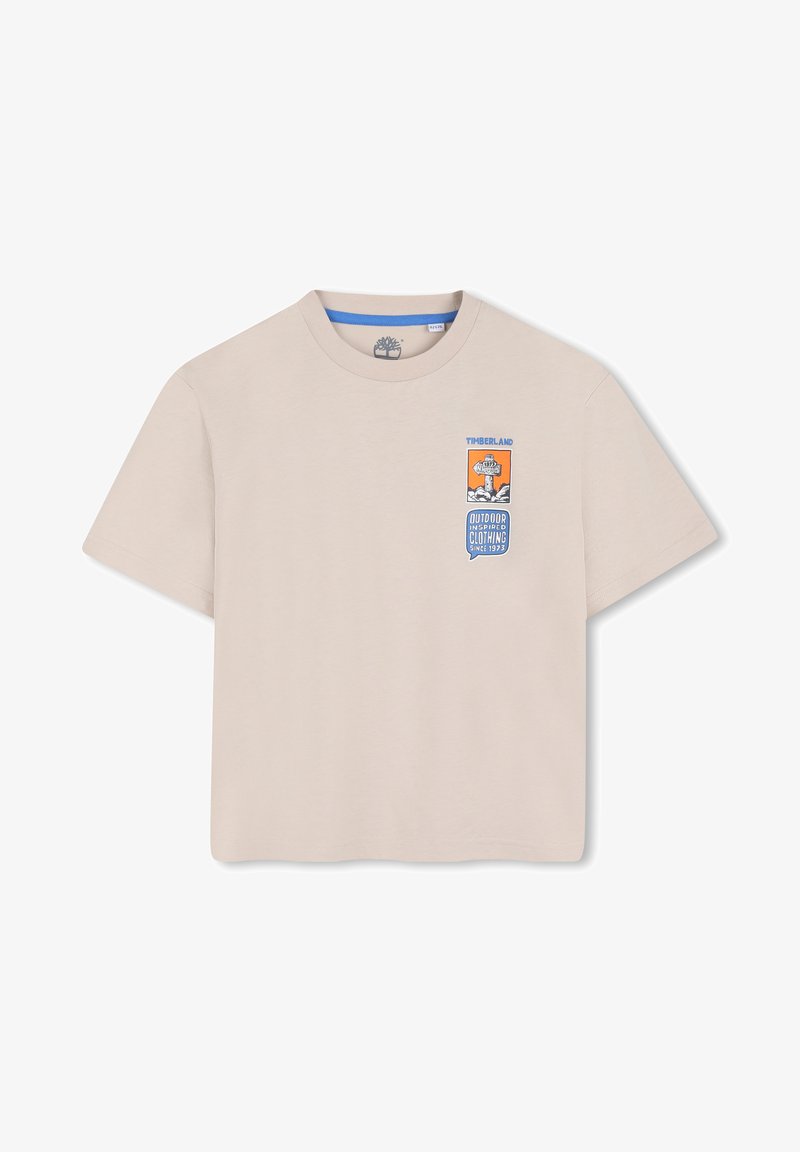 T-shirt beige à manches courtes en coton, avec un motif graphique comportant les mots « Timberland » et « OUTDOOR INSPIRED CLOTHING » en bleu et orange.