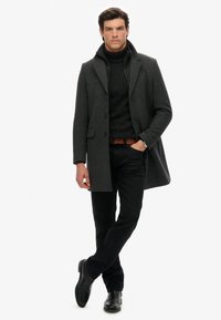 Grijze wollen blend jas met een geknipt kraag en knoopsluiting aan de voorkant. Draag hem over een donkere coltrui en zwarte broek, aangevuld met een bruine riem en zwarte laarzen.
