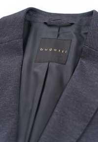 Navy blazer featuring a textured outer fabric and smooth inner lining. Includes a black label with gold "bugatti" text.