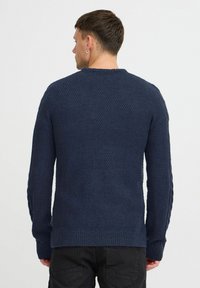 Pull en tricot marine avec un motif texturé, ourlet et poignets côtelés. Doté d'un col rond et de manches longues.