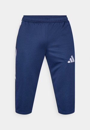 Tmavě modré sportovní kalhoty z hladké, lehké látky s délkou po polovinu lýtek a třemi bílými pruhy po stranách.