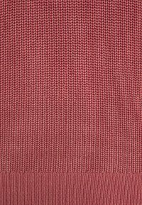 Sweter dziergany w gradientzie od ciemnego do jasnego mauve, z ribbowanym dołem i teksturowaną powierzchnią o jednolitym wzorze ściegów.