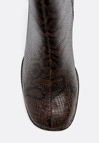 Stivale alla caviglia in pelle con motivo rettile marrone, punta quadrata, texture in pelle liscia e design elegante. Nessun hardware o dettaglio visibile.