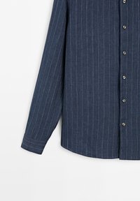 Navy blue long-sleeve shirt with white vertical pinstripes and buttons down the front against a white background.