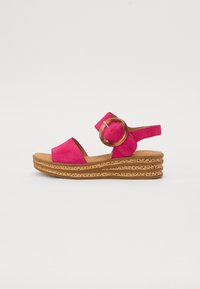 Roze nubuck wedge sandaal met een bandje en grote ronde metalen accent. Textuur kurken zool met gelaagde ribbels. Open teen design.
