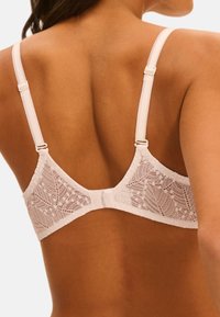 Bra bianco in pizzo con motivo floreale, spalline regolabili e chiusura a gancio sul retro. Texture liscia e dettagli di design delicati.