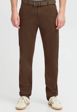 Brune bukser med en glat overflade og lige ben-design, der har bæltestropper og et matchende bælte. Sammen med beige sneakers.