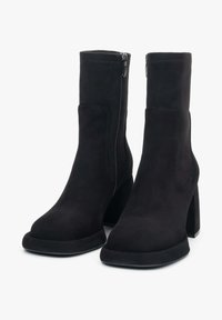 Zwarte enkellaarzen van zacht suede, met een vierkante neus, een chunkyleger en een zijrits voor gemakkelijke instap. Gladde matte afwerking.