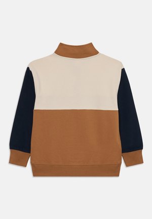 Sweatshirt col roulé avec des blocs de couleurs : partie supérieure beige, milieu et col marron, et manches et poignets bleu marine foncé.