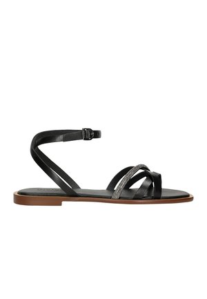 Sandalo nero con più cinturini incrociati, uno decorato con un elemento metallico. La suola è piatta e marrone, con una cinghia alla caviglia regolabile.