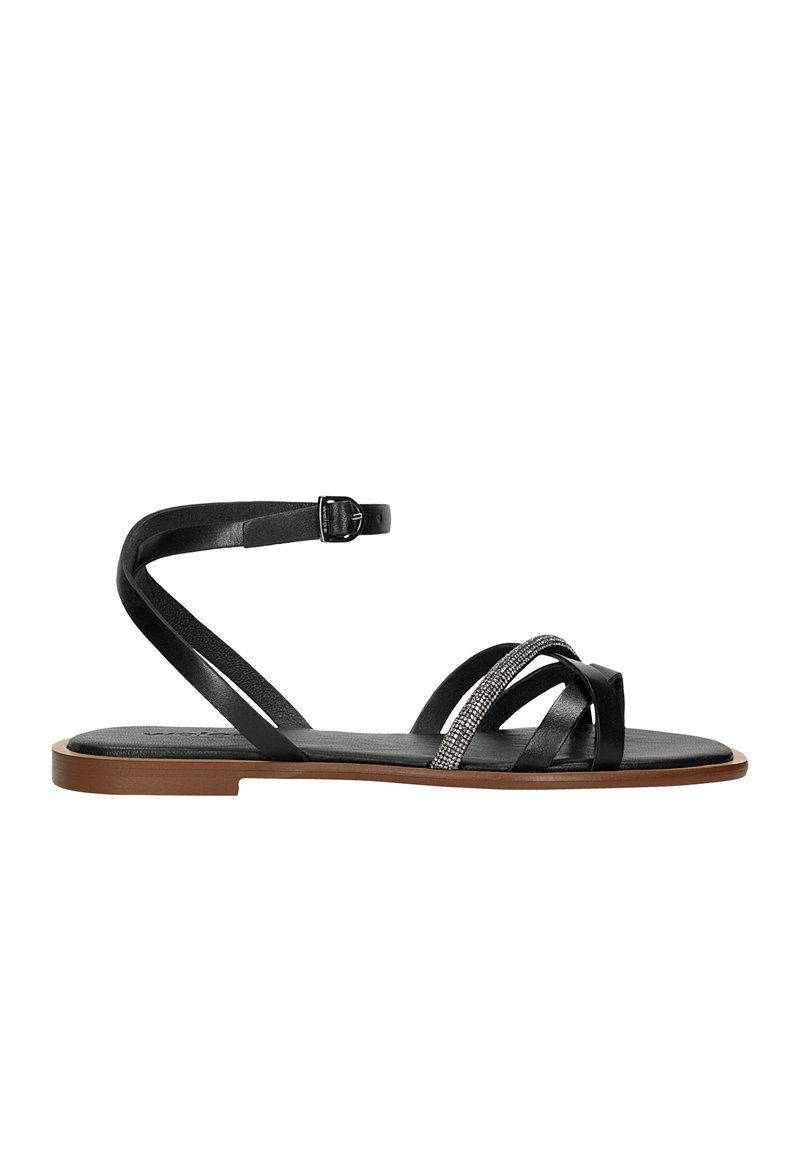 Černé sandály s několika kříženými pásky, z nichž jeden je zdobený metalickým akcentem. Podešev je plochá a hnědá, s přezkou na kotníku.