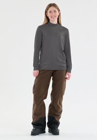 Harmaa pitkähihaista puseroa, jossa on hienovarainen kuvio, yhdistetty ruskeisiin housuihin, joissa on mustia yksityiskohtia ja rento istuvuus, sopii ulkoilmaaktiviteetteihin.