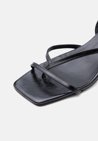 Μαύρο σανδάλι με τετράγωνη μύτη, δύο λεπτές γυαλιστερές λουρίδες μπροστά και λείο δερμάτινο πέλμα.