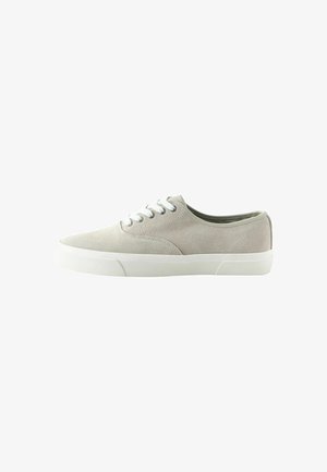 Lichtgrijze suède lage sneaker met witte rubberen zool en witte veters, gezien vanaf de buitenkant tegen een witte achtergrond.