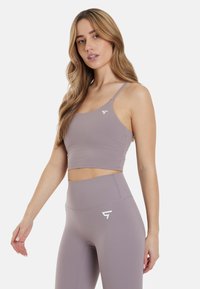 Athletic crop top and high-waisted leggings in muted lavender fabric. Features thin straps and a white logo accent. Smooth texture, fitted design.