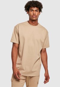 Beige katoenen t-shirt met een ronde halslijn, korte mouwen en een relaxte fit, gecombineerd met bijpassende beige broek. Lichtgewicht en eenvoudig ontwerp.