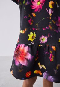 Must kleit erkroosa, kollase ja lilla erksate lillemustritega. Omab väljapaiskuvat seelikut ja vööosas graafilist detaili.