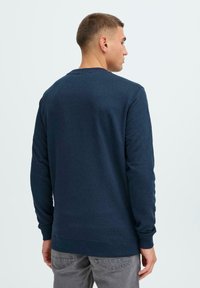 Felpa blu navy con maniche lunghe, colletto rotondo e polsini a coste. Realizzata in tessuto morbido, presenta un design semplice senza motivi.