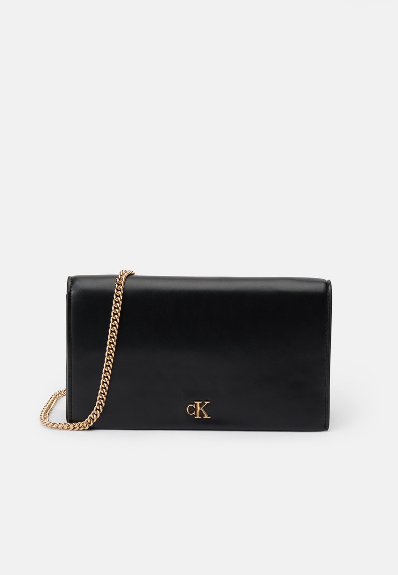 Svart lær clutchpose med gullkjede-stropp, rektangulær form, med et metallisk logo på forsiden. Glatt tekstur, minimalistisk design.
