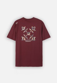 T-shirt bordeaux à manches courtes avec un motif croisé floral coloré et le logo "OXBOW" au dos, petite étiquette de marque sur l'épaule gauche.