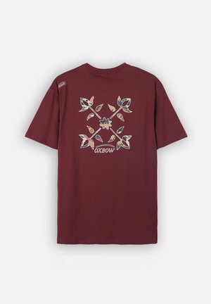 T-shirt bordeaux à manches courtes avec un motif croisé floral coloré et le logo "OXBOW" au dos, petite étiquette de marque sur l'épaule gauche.