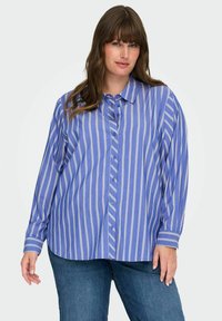 Camisa de botones de rayas azules con mangas largas. Rayas verticales blancas, dobladillo redondeado y mangas con puños. Textura de tela ligera.