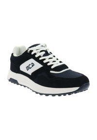 Zapatilla deportiva en blanco y negro con cordones blancos, parte superior de malla y ante, suela gruesa y logotipo de la marca en el panel lateral.