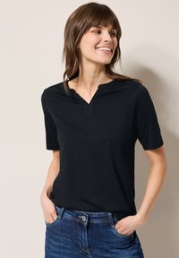 Haut noir à manches courtes avec un col en V et une texture douce. Assorti à un jean bleu avec une fermeture à bouton et des poches avant.