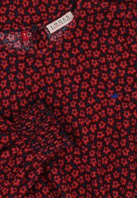 Rode en marineblauwe gebloemde blouse van stof met een klein bloemenpatroon en gathered mouwdetail. Tag zichtbaar met het merk "LOOXS REVOLUTION."