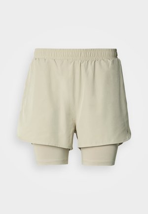 Helle beige sportliche Shorts mit elastischem Bund, mehrlagigem Design und integrierten Innenshorts. Glatte Textur mit minimalen Markendetails.