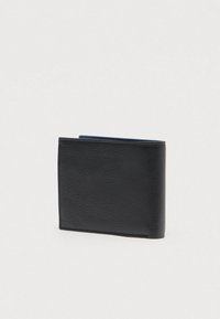 Black leather bi-fold wallet standing closed on a plain light background, showing textured grain finish.