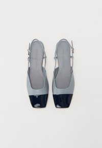 Talons slingback gris avec un bout carré, présentant un capuchon de pied en vernis marine et une semelle intérieure texturée grise. Sangle réglable avec boucle.